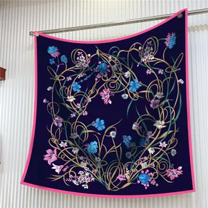 Élégant foulard en soie bleu marine avec motifs floraux et bordure rose sur rack