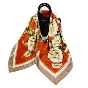 Elegante sciarpa in seta arancione da 90cm con camelie bianche su una borsa di lusso