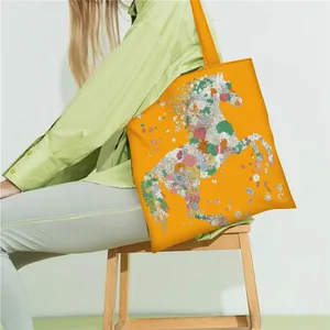 Detail of orange satin tote bag featuring a colorful floral horse print with shoulder strap
