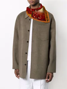 Detail of silk scarf with Van Gogh plum garden print worn around neck over a brown coat