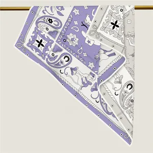 Detail of lavender paisley silk scarf draped over a gold bar showing textured twill fabric