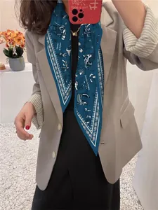 Detail of dark blue silk scarf with white nautical prints on a model in a gray suit