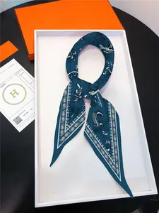 Detailed close-up of a blue nautical sailboat silk scarf in an elegant gift box packaging