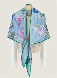 Detail of light blue silk scarf featuring giraffe and floral prints with green edges