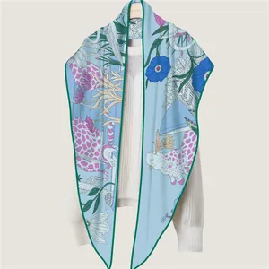 Elegant floral and giraffe print silk shawl in light blue, draped on a white sweater