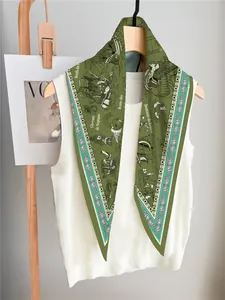 Detail of green silk scarf with nautical illustrations on a white knitted top