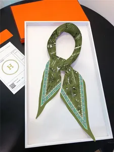 Detail of luxury silk twilly scarf with sailboat print and orange gift box
