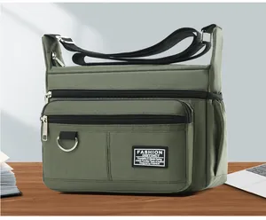 Detail of army green oxford cloth messenger bag with multiple zipper pockets on wooden desk