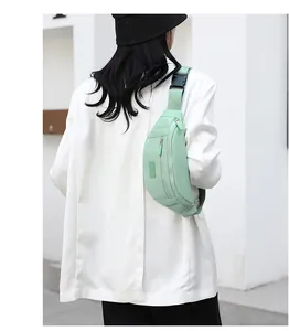 Outdoor model shot showing the light green nylon waist bag worn as a crossbody pack