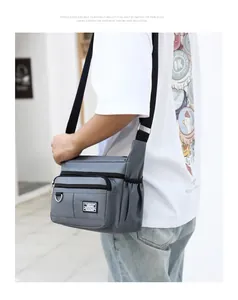 Detail view of grey water-resistant oxford crossbody bag with side pocket and logo