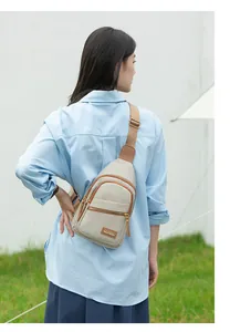 Detail of a beige multi-pocket crossbody sling bag with adjustable strap on a female model