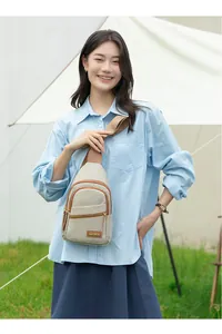 Detail of beige nylon crossbody chest bag with brown zipper trim and brand plate