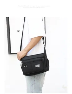 Detail of black waterproof crossbody bag featuring multi-zipper pockets and D-ring hook