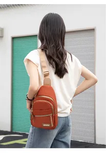 Close-up of caramel nylon chest bag featuring three zippered pockets and metal logo