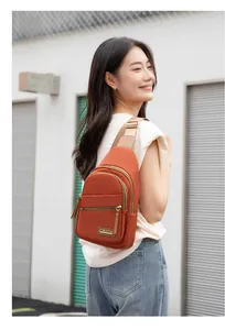 Close-up of burnt orange nylon chest bag with golden metal zippers and adjustable strap