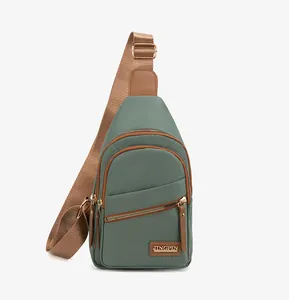 Detailed close-up of green nylon chest bag featuring metal zippers and leather pullers