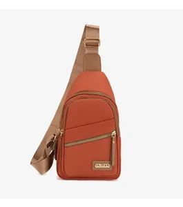 Detail view of brick red crossbody chest bag with three zipper pockets and adjustable strap