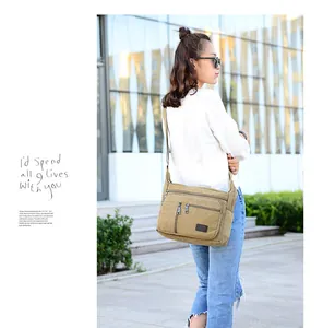 Outdoor model display of a khaki canvas crossbody bag with multiple zipper pockets