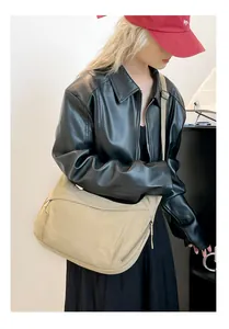 Detalle de un bolso tote grande de nylon beige con correas ajustables y cremalleras