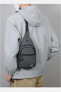 Detail of grey oxford chest bag featuring earphone port and sport logo on modern sling bag