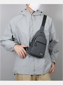 Detailed view of dark grey oxford chest bag with headphone port and multiple zipper layers