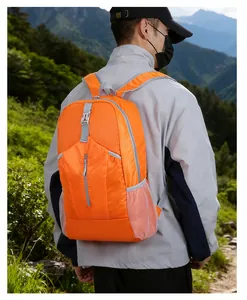 Outdoor waterproof orange hiking backpack shown on a model against a mountain landscape