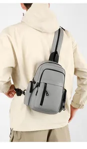 Rear view of a man wearing the grey minimalist crossbody bag with dual front zippers