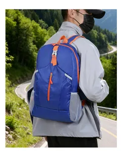 Blue ultra-lightweight foldable backpack with orange straps in a forest hiking scene