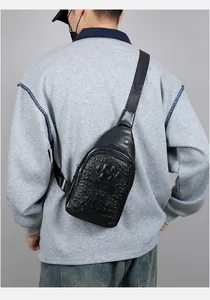 Rear view of man wearing a black faux crocodile leather sling bag with adjustable strap