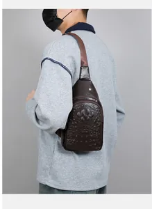 Detail of dark brown faux leather chest bag showing crocodile embossed texture and zipper