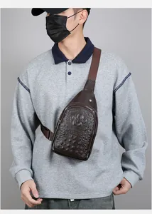 Detail of dark brown faux crocodile leather chest bag with adjustable strap and metal zipper
