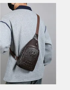 Detail of dark brown men's chest bag featuring crocodile texture and adjustable strap