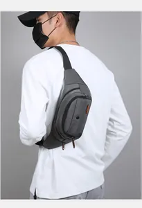 Detail of dark grey waterproof waist bag showing multiple zippers and durable fabric texture