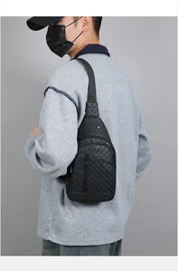 Detail of black crossbody chest bag with embossed geometric texture and metal zippers
