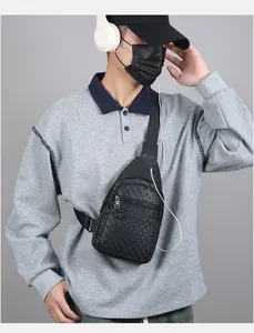 Detail of black embossed chest bag showing zipper compartments and earphone port