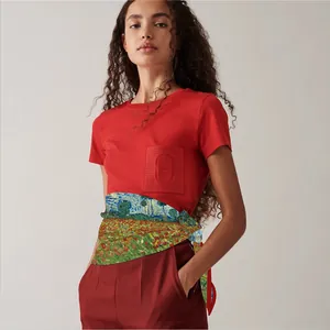 Detail van artistieke zijden sjaal om de taille over een rood shirt met korte mouwen