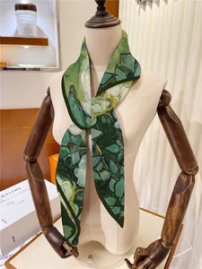Gros plan d'un foulard en soie français noué sur un mannequin avec motifs de fleurs vertes