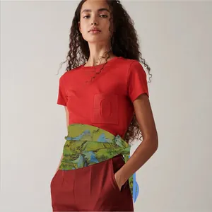 Detail of a landscape pattern silk scarf tied around waist with red t-shirt