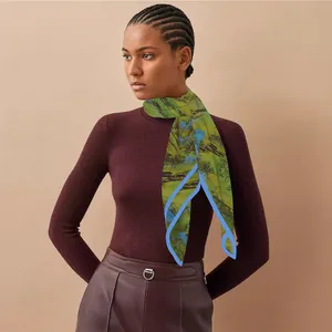 Detail of silk landscape scarf featuring blue and green nature scenery on a green base