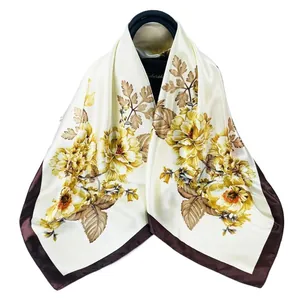 Detail eines eleganten 90cm Seidentuchs mit gelben Blumenmustern und dunkelbraunem Rand