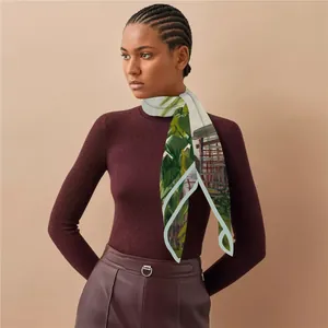 Detail of artistic floral print silk scarf styled on model with deep burgundy knitwear