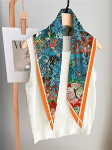 Detail of printed silk scarf with tropical garden motifs and bright orange borders
