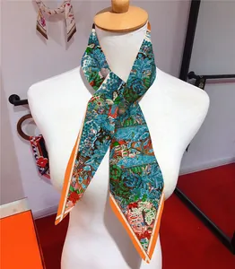 Detail of floral printed twilly silk scarf tied in a bow on a white mannequin