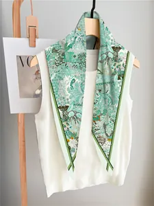 Detailed view of silk scarf with green jungle botanical prints on a wooden hanger