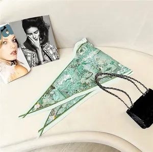 Detailed close-up of a mint green floral silk scarf styled with a luxury black handbag