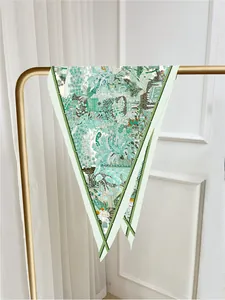 Detail view of large silk scarf featuring tropical jungle patterns and bamboo borders