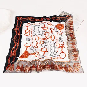 Detailed view of large silk square scarf with horsebit print and elegant fringe pattern