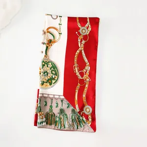 Detail of red and white silk scarf with golden horseshoe chain and tassel patterns