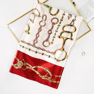 Detailed flat lay of satin scarf with horse bit, gold chain and red border pattern