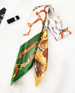 Detail of silk scarf featuring gold horsebit and chain patterns on emerald satin fabric